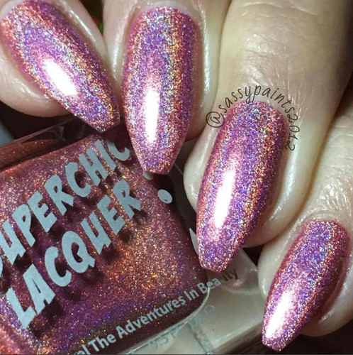 Flutter Nail Polish, holographic glittery nail polish on nails with a burst of pink, purple, and gold colors.