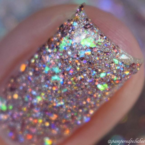 Love Stinks Nail Polish, close-up of a fingernail coated with glittery holographic nail polish with multicolored sparkles.