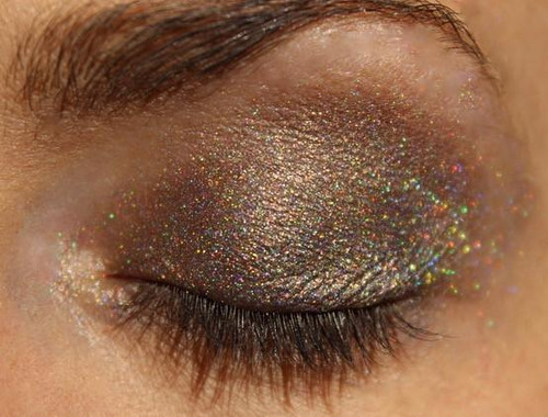 Coco Holographic Eyeshadow, close-up of a closed eye with shimmering, holographic makeup on eyelids.