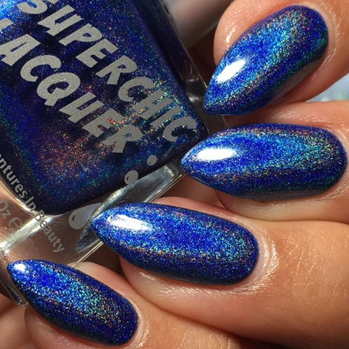 Throwing Shade Nail Polish, vibrant blue holographic nail polish with multicolored glitter, applied on manicured nails.