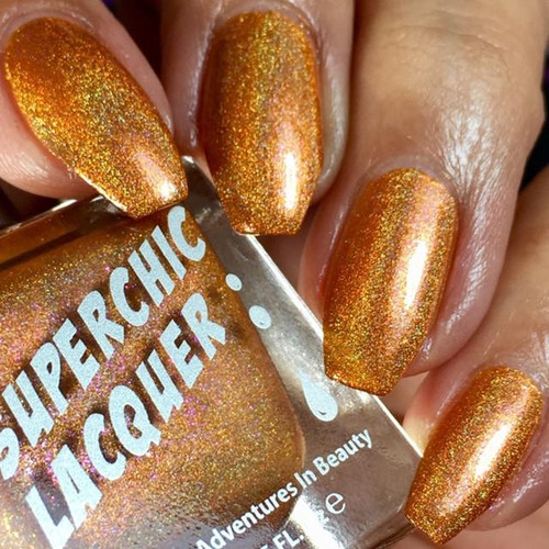 Jinxed Nail Polish, vibrant holographic orange nail polish on manicured nails.