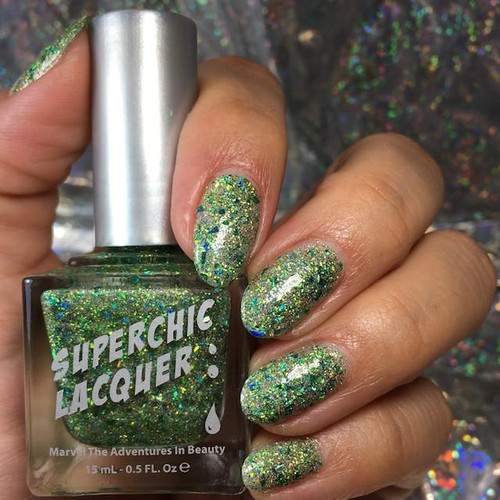 Charmed Holographic Nail Polish, hand with nails painted in holographic sparkly green and silver nail polish, holding the nail polish bottle.