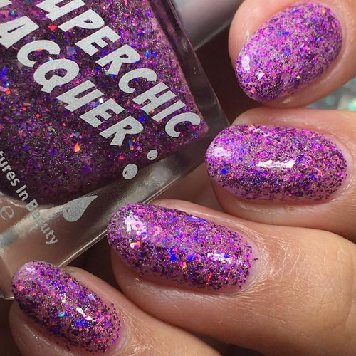 Trapped In An Enchantment Holographic Nail Polish, close-up of hand with nails painted in purple holographic glitter nail polish with multicolored sparkles.