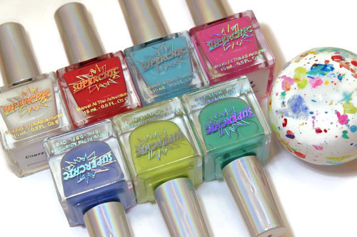 Suck It Nail Polish collection, colorful bottles of nail polish in red, blue, pink, yellow-green, and teal with metallic caps, and a colorful speckled ball.