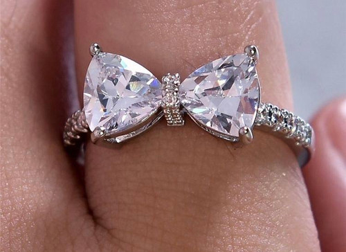 Dazzling Bow Ring - White Faux Diamond - 925 Sterling Silver, close-up of a silver ring with a bow-shaped design adorned with white faux diamonds on a finger.