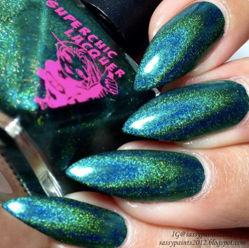 No Rest For The Wicked Nail Polish, close-up of turquoise and green holographic nails with glitter of the product on fingers.