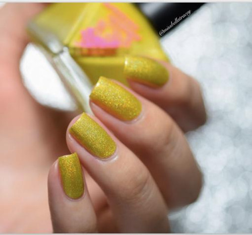 Electrifried Nail Polish, close-up of a hand with glittery yellow-green nails holding a transparent nail polish bottle with pink powder inside.