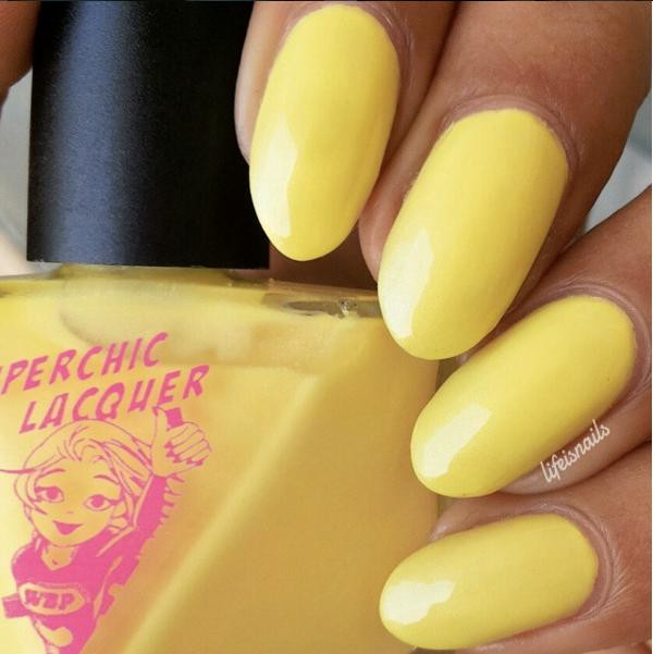 Law Of Nature Nail Polish, hand with yellow painted nails and a yellow nail polish bottle in the background.