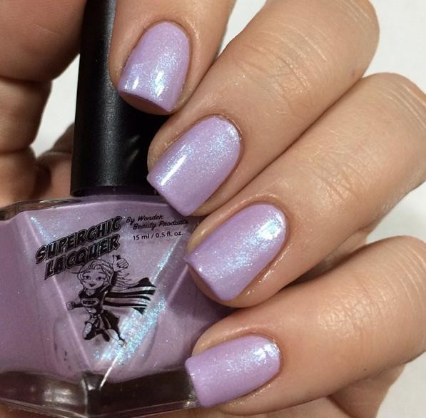 Shrinking Violet Nail Polish, bottle of shimmering pastel purple nail polish with sparkly finish held near manicured nails