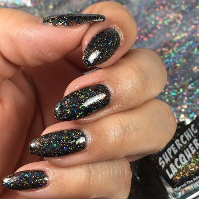 Bittersweet Oil Spill Nail Polish, close-up of a hand with nails painted in black holographic glitter nail polish.