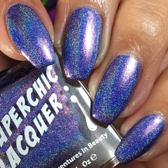 Juju Nail Polish, holographic purple-blue glitter nail polish on manicured fingernails.