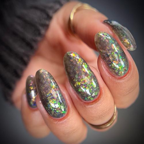 Pumpkin Patch Near Me Halloween Nail Polish, close-up of glittery holographic nail art on fingers with gold rings.