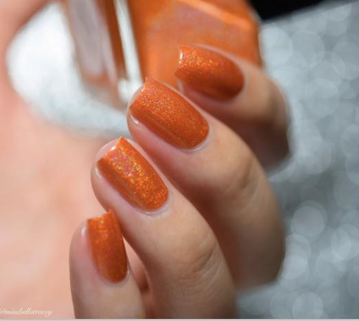 Reverse Polarity Nail Polish, close-up of a hand with orange holographic nail polish on fingernails. 