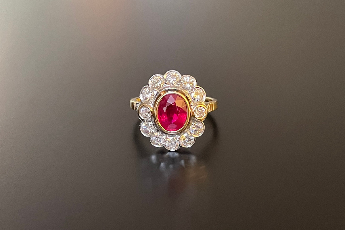 A Wonderful Ruby and Diamond Cluster Ring 
Comprising central oval cut ruby, surrounded by twelve round brilliant cut diamonds bezel set.
Having two small brilliant cut diamonds set to each shoulder.
18ct white and yellow gold.
