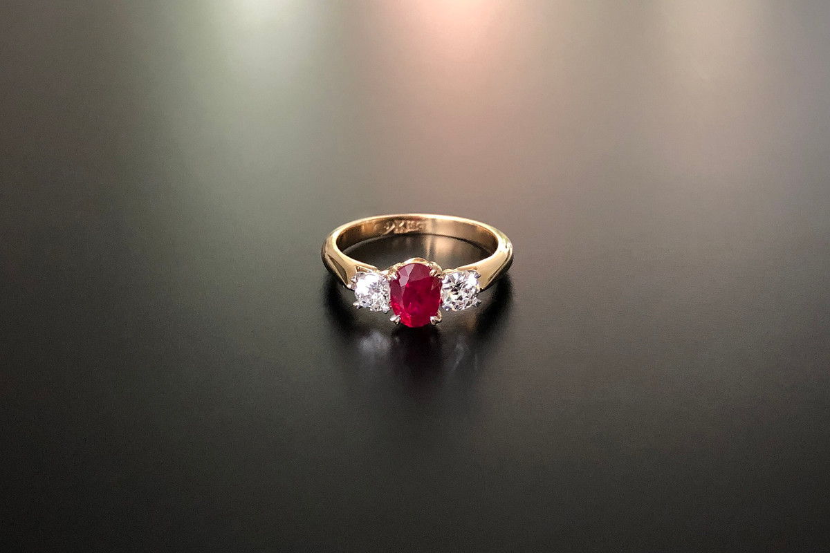 A Classic Three Stone Ruby and Diamond Ring
Comprising a central oval Burmese Ruby with an Old Brilliant Cut diamond to the shoulders.
Ruby weight: 1.01cts
Total diamond weight: 0.42cts, J-K, SI.
Claw setting
18ct yellow gold.
Total weight: 3.95gms
Size: M1/2