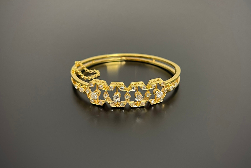 An Elegant Diamond Bangle
Oval hinged form
Having four interlinked open work hexagonal panels.
Each having a central old cut diamond with small rose cut diamonds to the border
18ct gold
