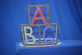 A "Premier Crowns" design. Alphabet blocks tiara with adjustable band. 6" tall