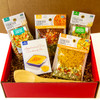 Close-up of Get Well Gift Box contents, highlighting the colorful soup mixes, cornbread mix, and cheerful, red packaging
