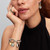 Modelo luciendo el Charm Pandora Medallón Amanecer en metal chapado en oro y color blanco en una pulsera de plata - 763859C01