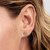 Modelo luciendo los Pendientes Pandora de Botón Halo Corazón chapados en oro con circonitas transparentes vista lateral - 264363C01