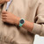 Modelo luciendo vista lateral del Reloj Swatch Hint of Mint con esfera negra y brazalete de silicona verde - SO29L103