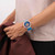 Modelo luciendo el Reloj Swatch Swatch Neon Hielo con esfera violeta y brazalete de silicona azul en vista lateral - SB01K400
