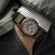 Modelo luciendo el Reloj Khaki Field Mechanical con brazalete textil verde y esfera marrón en vista frontal - H69449961