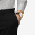 Modelo luciendo el Reloj TISSOT PR 100 40mm con caja dorada esfera plateada y correa de piel marrón en vista lateral - T1504103639100