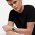 Modelo luciendo el Reloj Tommy Hilfiger con brazalete de eslabones con esfera negra y brazalete chapado en oro - 1792241