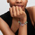 Modelo luciendo una pulsera con múltiples charms navideños, incluyendo el Charm Pandora Bebida de Galleta de Jengibre - 795062C01