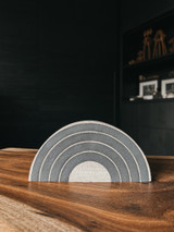 Half-moon stoneware form painted with black rings in a rainbow arc design.