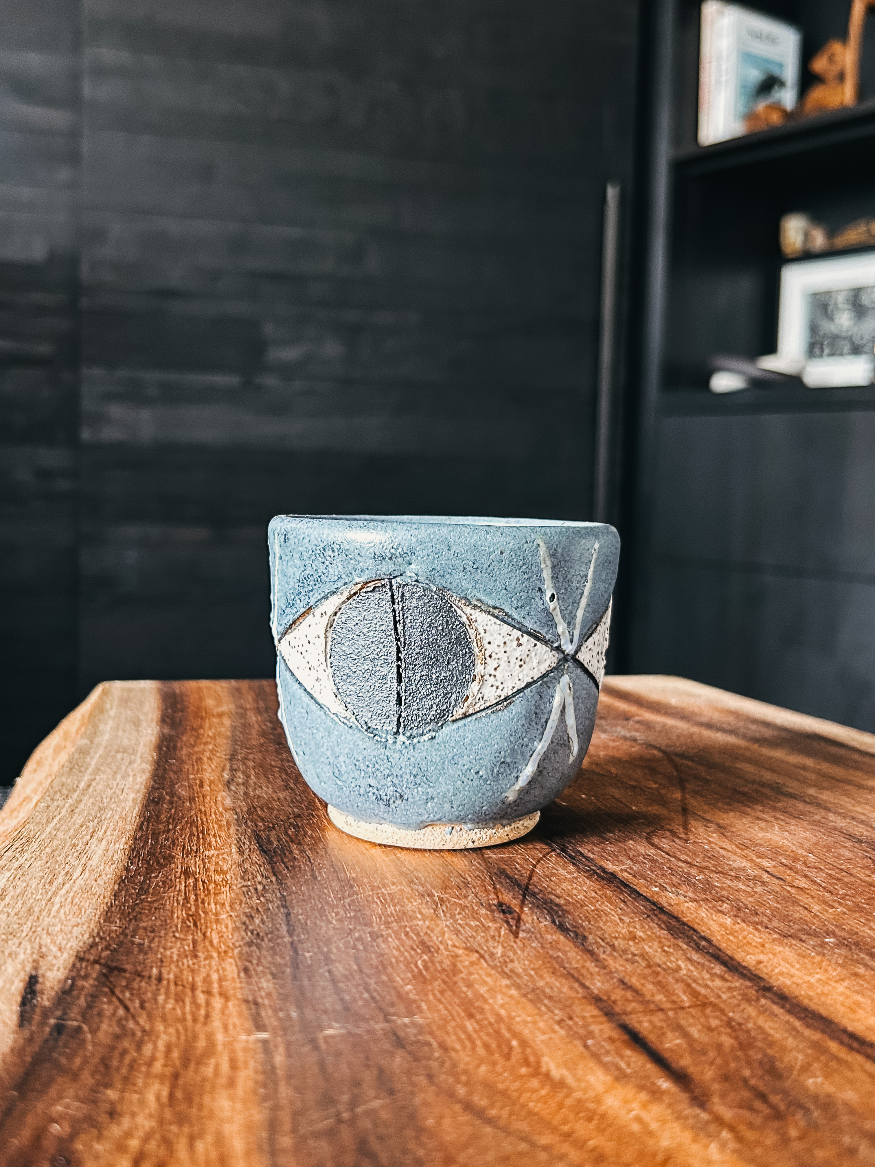 A handcrafted slate ceramic cup featuring a sketched eye motif by artist Matthew Ward.
