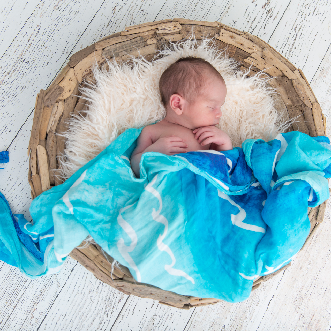Sleeping baby in basket swaddled in Coco Moon hawaii Nalu baby Swaddle