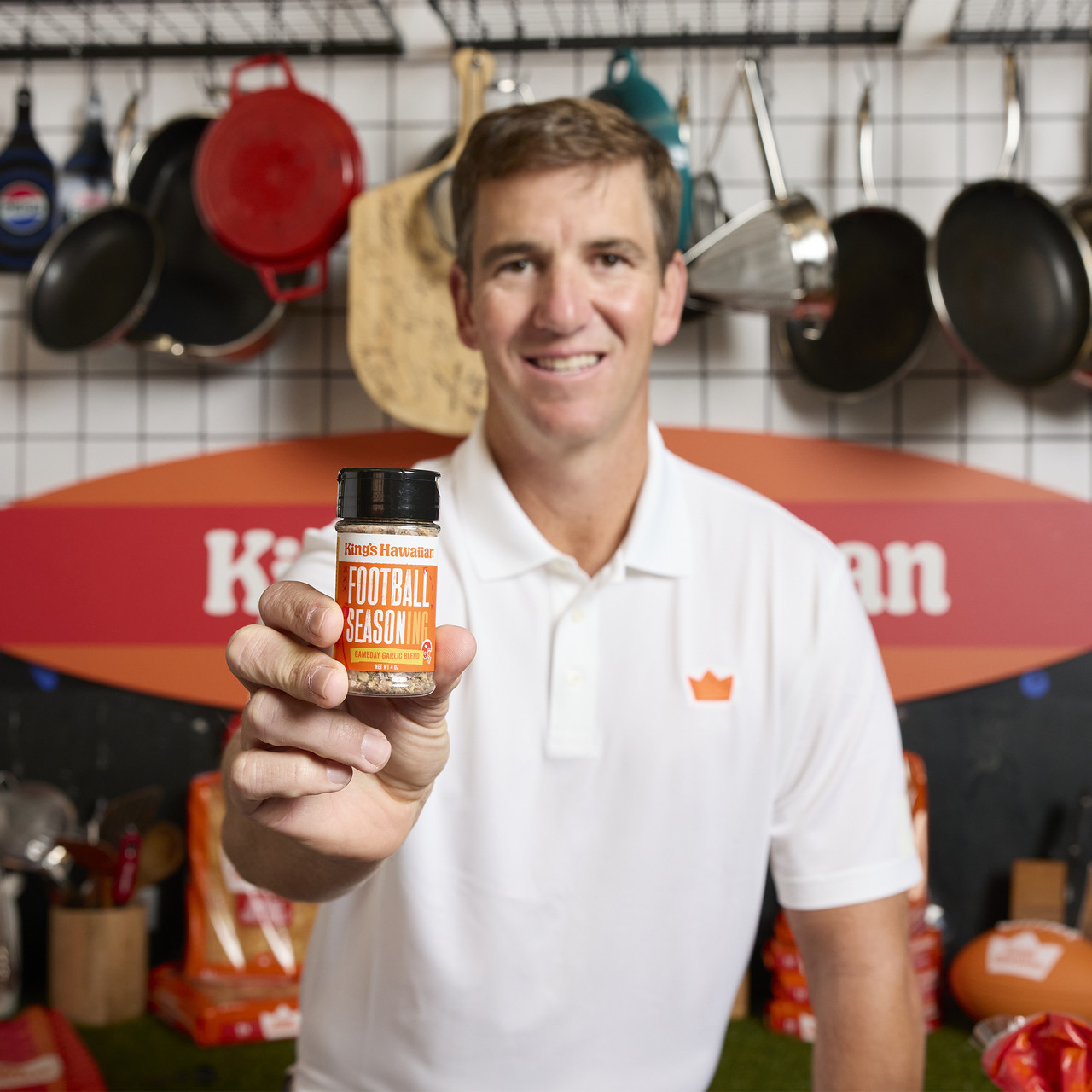 Image of Eli Manning holding King's Hawaiian Football Seasoning, 4 oz container on a kithen background