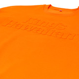 King's Hawaiian orange crewneck with embossed logo on the chest, close up King's Hawaiian orange crewneck with embossed logo on the chest, close up