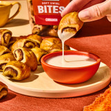 King's Hawaiian Soft Swirl Cinnamon Bites dipped in creamy icing, featuring bite-sized cinnamon rolls with sweet cinnamon filling served as a snack or breakfast treat.
