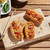 3 Hot dogs on King's Hawaiian Hot Dog Buns sitting on top of a wooden serving plate on a hardwood table