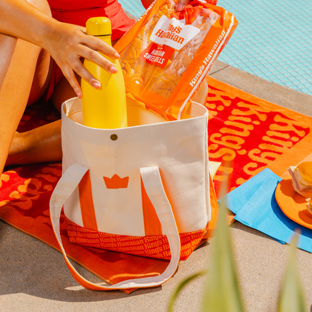 Lifestyle image of King's Hawaiian mini tote bag with crown graphic and wordmark, front