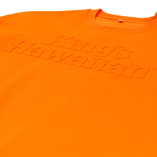 King's Hawaiian orange crewneck with embossed logo on the chest, close up King's Hawaiian orange crewneck with embossed logo on the chest, close up