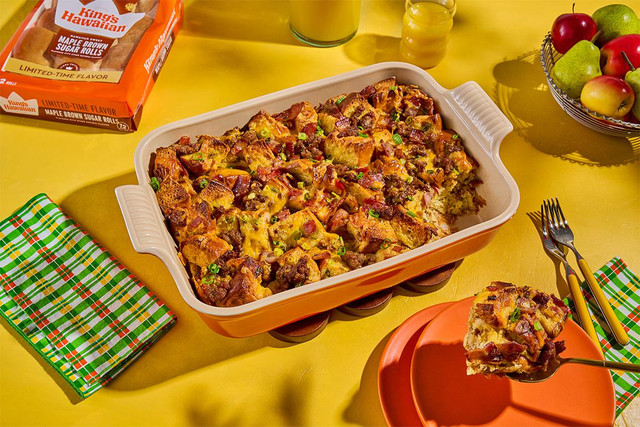 Friendsgiving breakfast casserole made with King's Hawaiian Maple Brown Sugar Rolls, sausage, bacon, ham, cheddar, and green onions in a baking dish