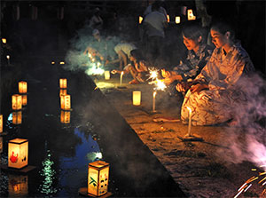 Japanese women floating lanterns in river 