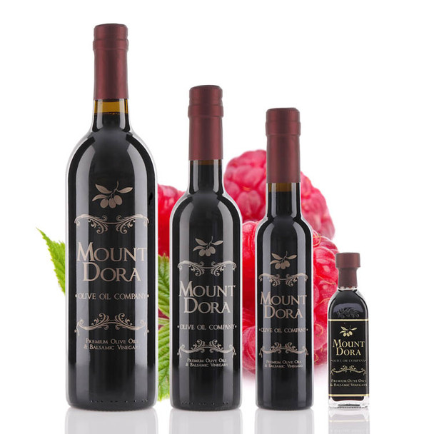 Four different size bottles of Mount Dora Olive Oil Company Raspberry Dark Balsamic Vinegar.