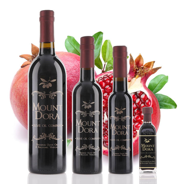 Four different size bottles of Mount Dora Olive Oil Company Pomegranate Dark Balsamic Vinegar