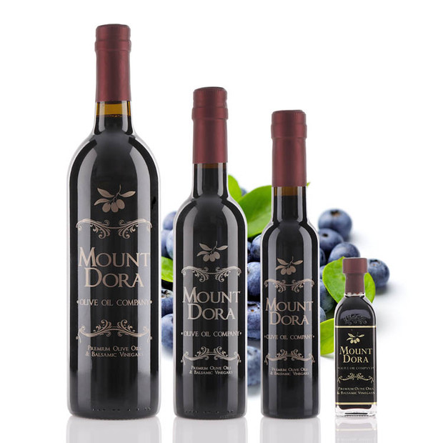 Four different size bottles of Mount Dora Olive Oil Company Wild Blueberry Dark Balsamic Vinegar