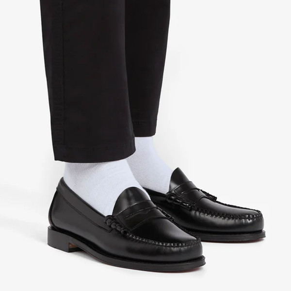 Man wears Bass Weejuns Men's Heritage Larson Penny Loafers with Leather Sole in Black Leather