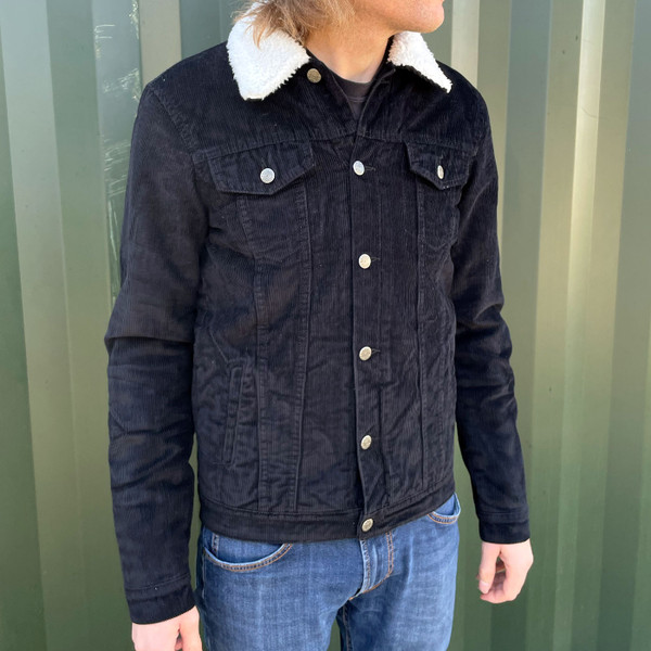 Man wears Madcap England Woburn Sherpa Lined Trucker Jacket in Black