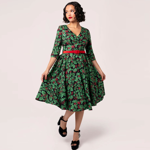 Model wears Hell Bunny Nicole Christmas Holly Print 50s Doll Dress in Black and Green