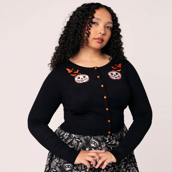 Model wears Hell Bunny Hollow 50s Style Cropped Halloween Pumpkin Cardigan in Black