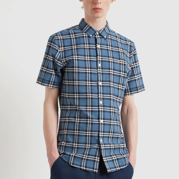 Man wears Farah Vintage Brewer Retro 3 Colour Check Short Sleeve Oxford Shirt in Blue Tide
