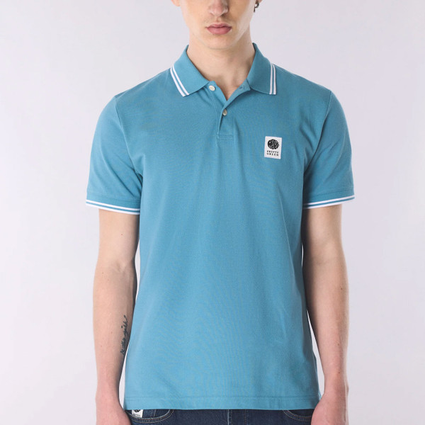 Man wears Pretty Green Rayner Men's Mod Twin Tipped Pique Polo Shirt in Blue